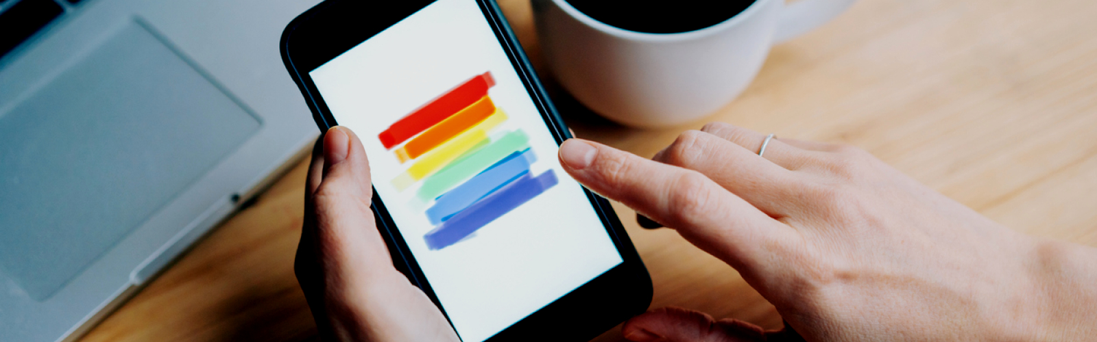 Regenboog op een smartphone met een tas koffie ernaast