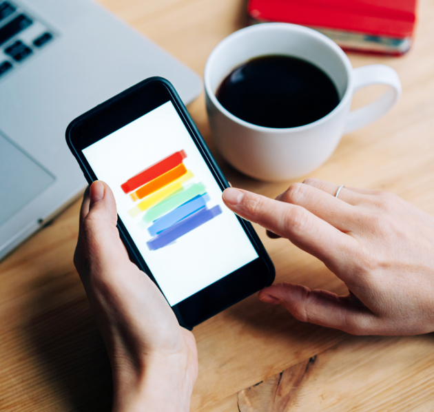 Regenboog op een smartphone met een tas koffie ernaast